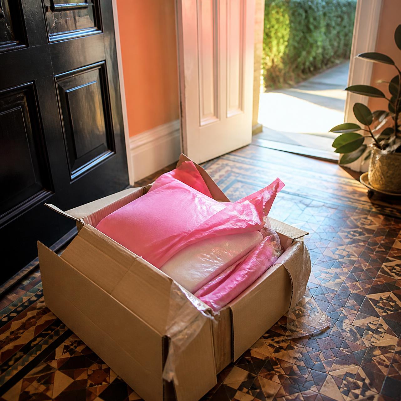 A parcel just opened on a hallway floor, product half out of the box